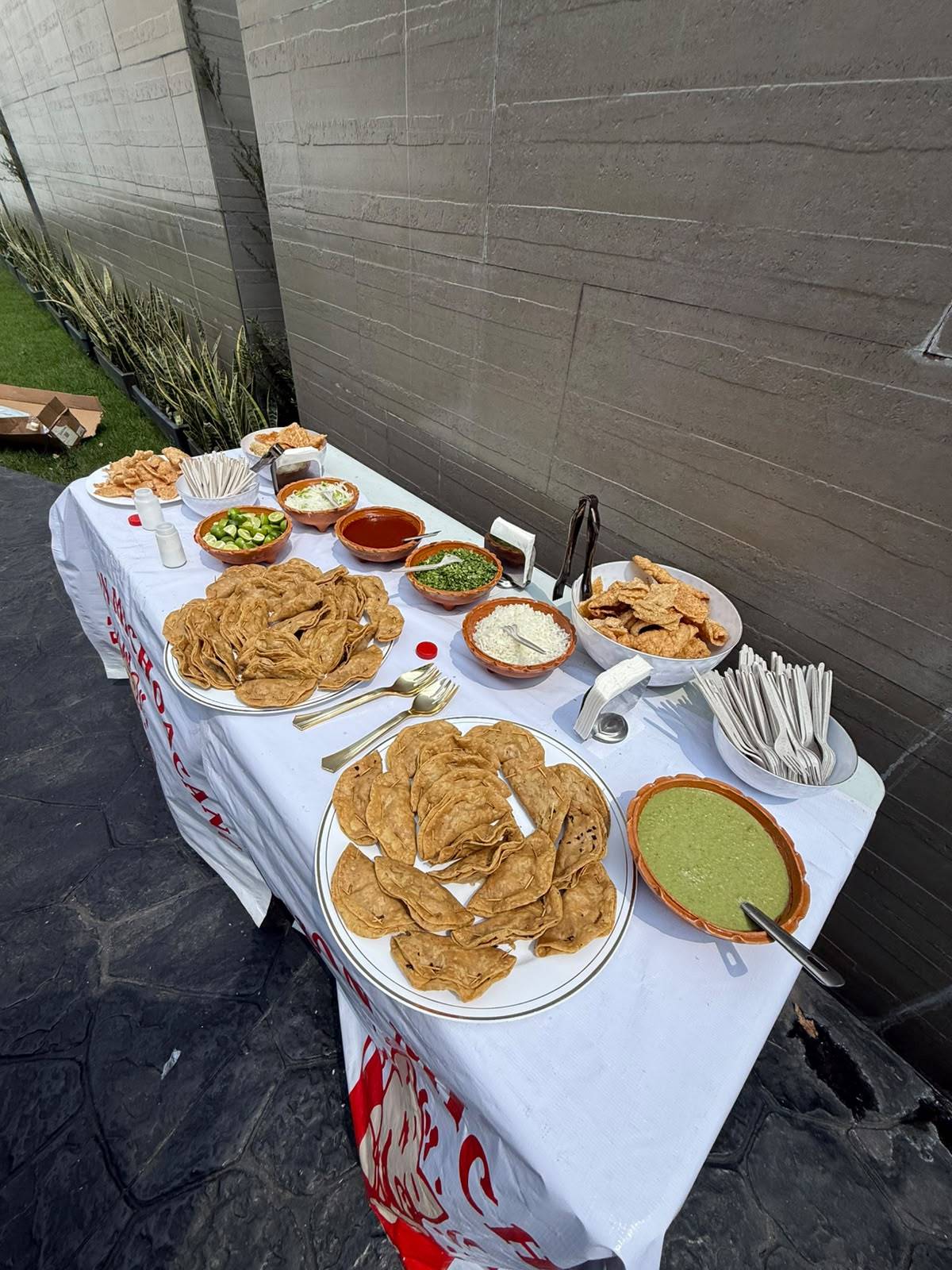 Mesa de servicio con tacos dorados, chicharrón y salsas en cazuelitas de barro